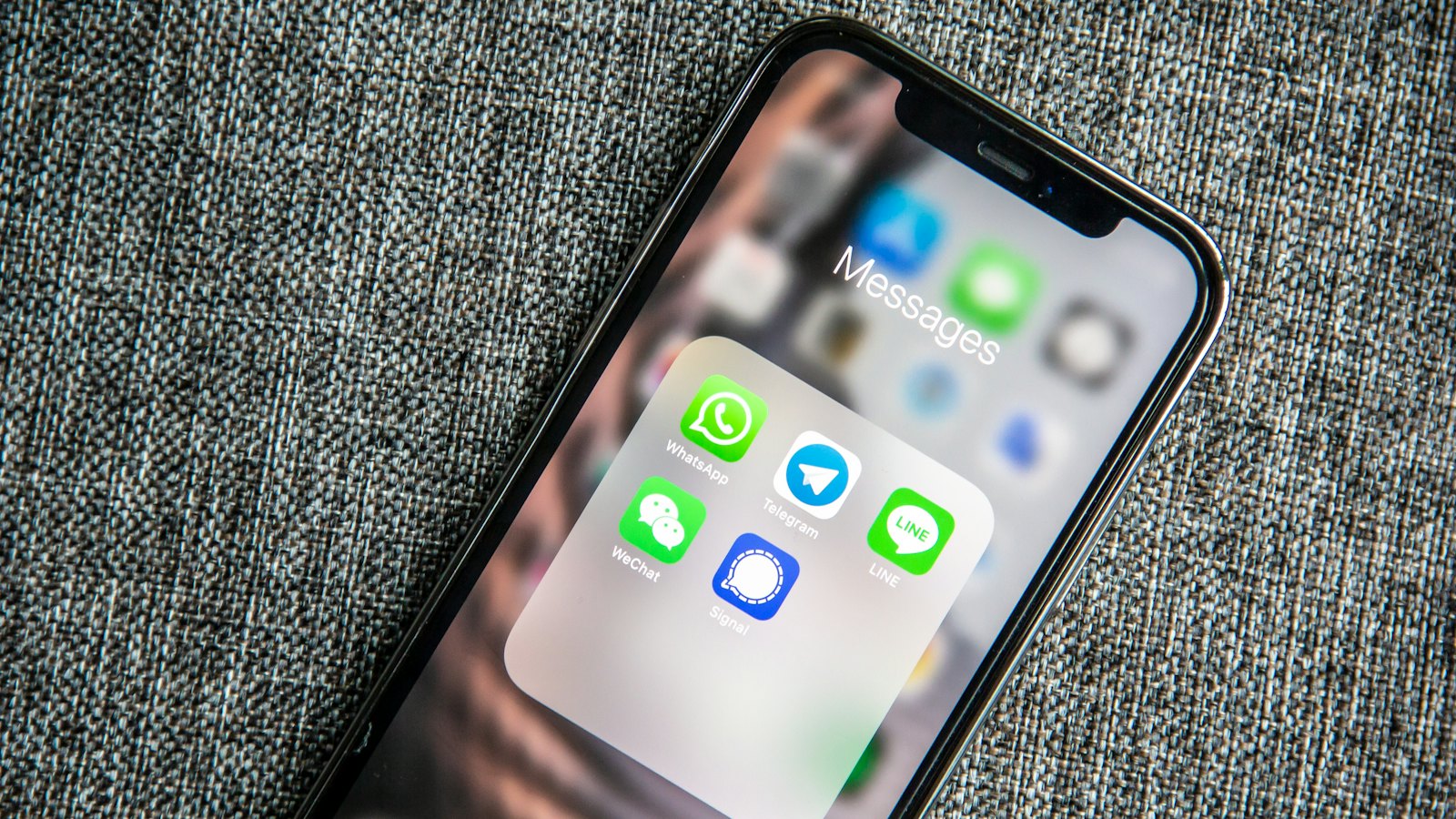 Móvil con una carpeta de aplicaciones de mensajería, entre ellas WhatsApp